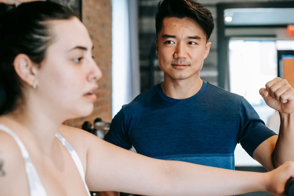 Huấn luyện viên hướng dẫn hội viên mới tập trên máy