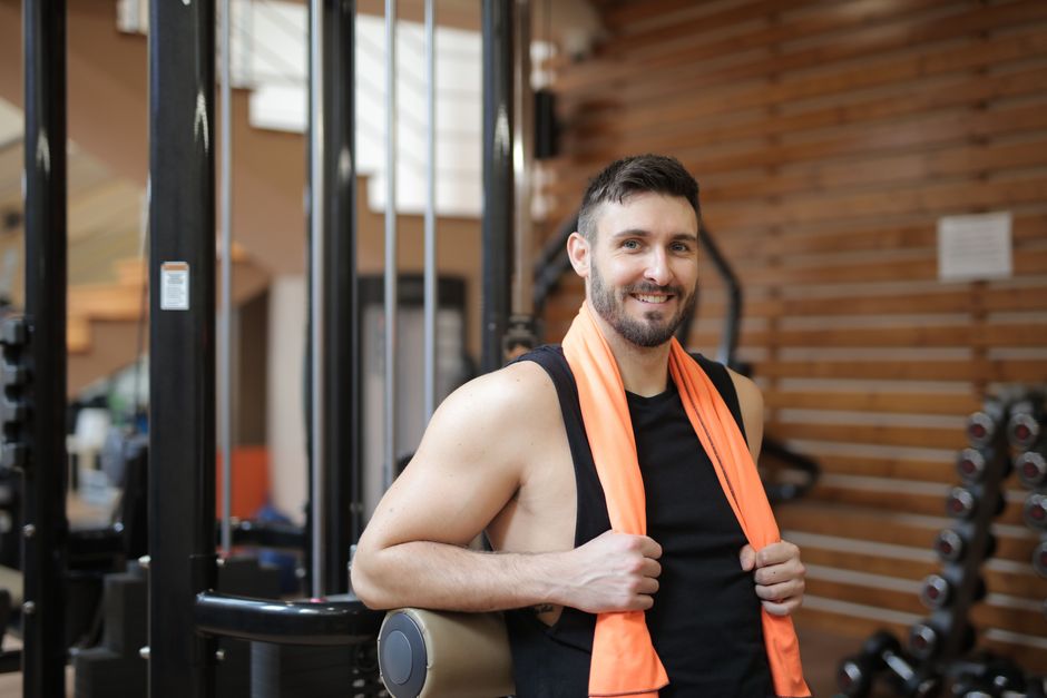 Huấn luyện viên mỉm cười đứng cạnh thiết bị trong phòng gym
