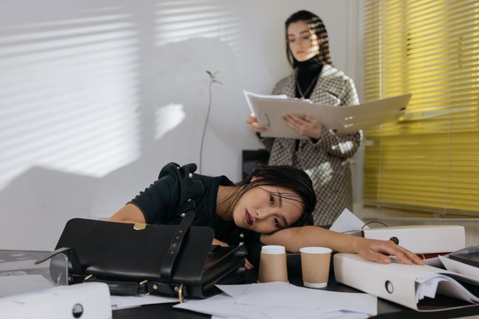 Nhân viên mệt mỏi gục xuống bàn giữa đống tài liệu
